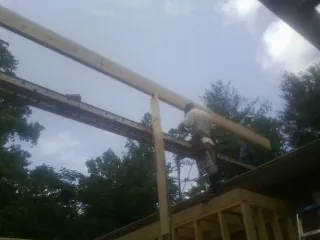 Carpenter setting a ridge beam over a new addition frame — Ice Dam Removal by Roofing Brothers in Norfolk
