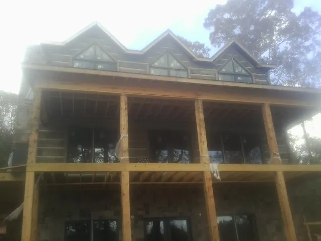 Dormers and porch framing on a large log home under construction — Roof Coating work by our crew in Norfolk